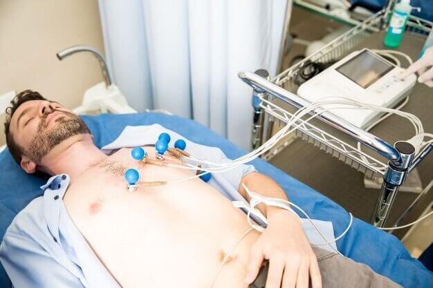 persona acostada con electrodos en el pecho conectada a un ECG