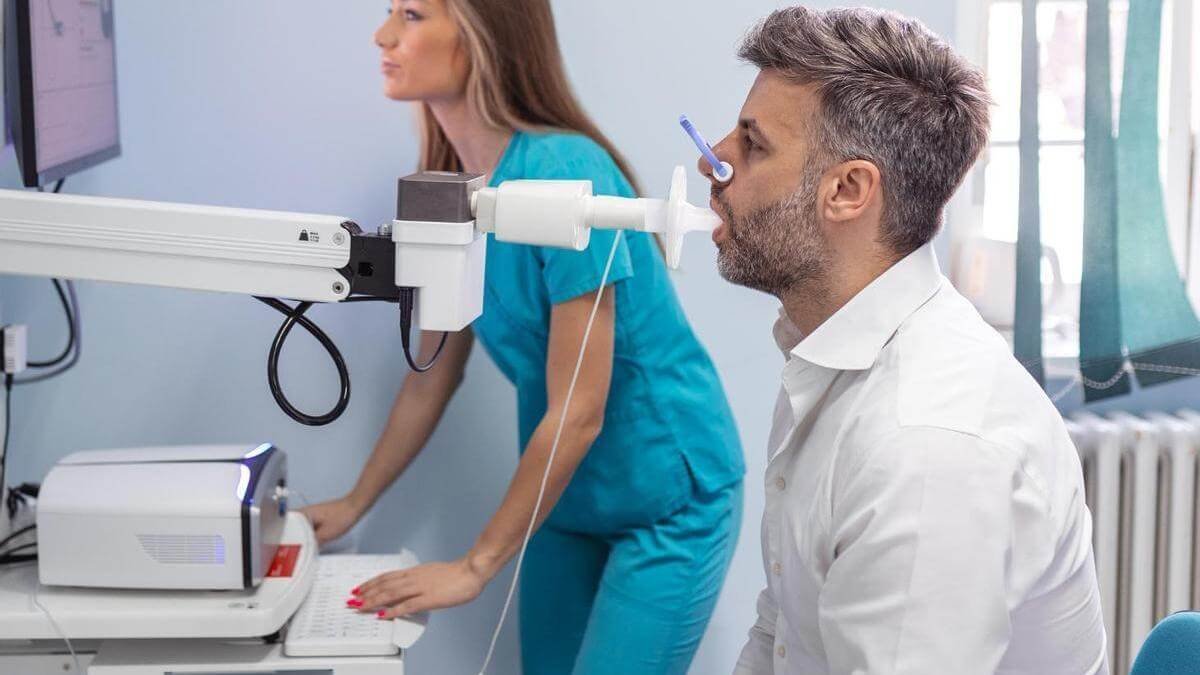persona soplando en un espirómetro, guiado por un Doctor